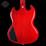 The rear view of an electric guitar body featuring a glossy red finish with a visible wood grain texture, a black pickguard, and a silver tuning peg, set against a solid black background.