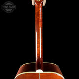Close-up of the back of an acoustic guitar showing the glossy reddish-brown wood backplate and neck joint against a black background, with a Tone Shop watermark in the top left.