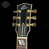Close-up of a Gibson acoustic guitar headstock with gold tuning pegs and Hummingbird branding on a black background.
