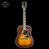 A Nordost acoustic guitar with a natural sunburst finish, featuring intricate floral inlays on the lower bout, a dark fretboard, and gold-toned tuning pegs, set against a solid black background with a Tone Shop watermark in the top left corner.