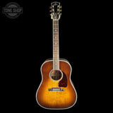 A vintage-style acoustic guitar with a natural sunburst finish, shown vertically against a solid black background. The brand logo on the headstock reads 'Taylor'.
