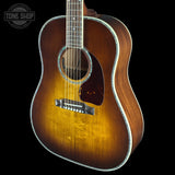 A classic acoustic guitar with a natural sunburst finish, shown from a three-quarters angle against a solid black background. A 'TONE SHOP' watermark is in the top-left corner.