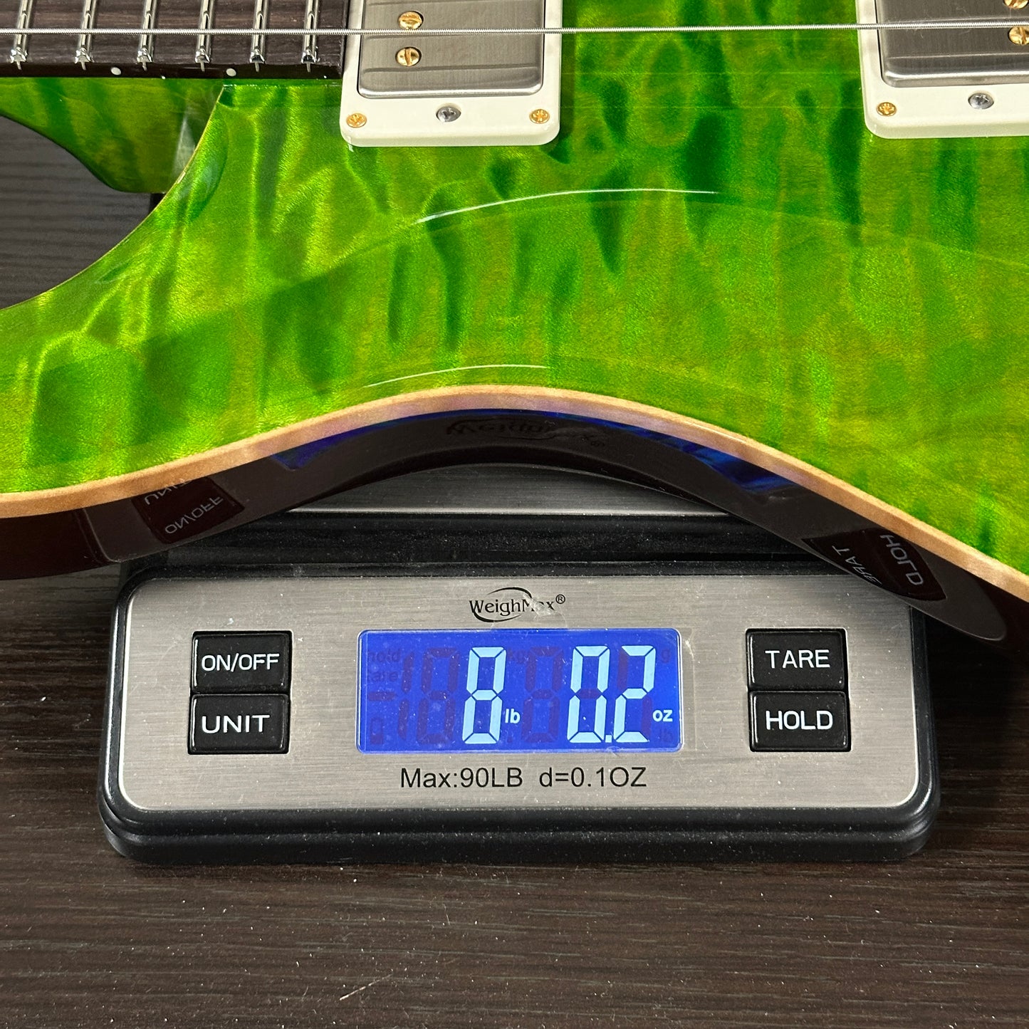 Green electric guitar on a digital scale displaying weight.