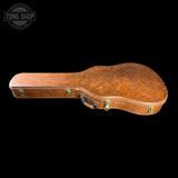 A vintage brown guitar case with a heavily worn, distressed leather-like finish and brass latches, shown against a solid black background with a Tone Shop watermark in the top-left corner.