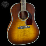 A classic acoustic guitar with a natural sunburst finish, featuring a dark brown outer edge fading to a warm golden-yellow center, set against a solid black background.