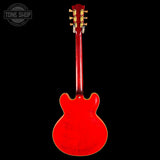 A red electric guitar shown from the back against a solid black background, with a Tone Shop watermark in the upper left corner.