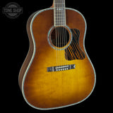 A classic acoustic guitar with a natural sunburst finish, featuring a black pickguard and silver metal trims, shown against a solid black background.