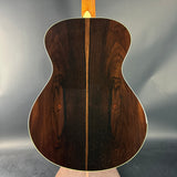 Back view of a wooden acoustic guitar on a gray background