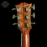 Close-up of the headstock of a Gibson acoustic guitar, showing six gold tuning pegs, serial number 20845047, and the Gibson logo on a black background.
