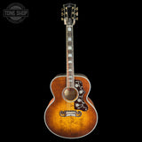A Gibson acoustic guitar with a natural sunburst finish, featuring ornate mother-of-pearl pickguard details and a black headstock, shown against a solid black background with a Tone Shop watermark in the top left corner.