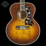 A vintage-style acoustic guitar with a sunburst finish, featuring intricate silver floral inlays on the pickguard and headstock, shown against a solid black background.