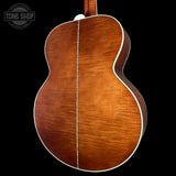 The back of an acoustic guitar with a rich, warm brown wood finish and white binding, shown against a solid black background with a Tone Shop watermark in the top left corner.