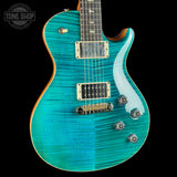 A turquoise blue electric guitar with a flamed maple top, gold hardware, and a dark fretboard, shown against a black background with a Tone Shop watermark in the top-left corner.
