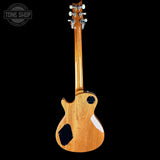 A single-cutaway electric guitar shown from the back, featuring a glossy natural wood finish and black pickguard, set against a solid black background with a Tone Shop watermark in the top-left corner.