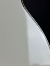 Close-up of a glossy white curved surface with a thin dark edge and a small visible imperfection or droplet on the finish.