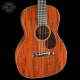 A close-up of an acoustic guitar body showing a rich, warm reddish-brown wood grain finish, with a dark pickguard and silver bridge, set against a solid black background. A 'TONE SHOP' watermark is visible in the top-left corner.