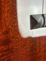 Close-up of a brushed silver metal fixture or bracket mounted on a reddish-brown wood surface with a white painted section visible at the top left.