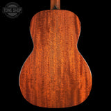 The back of a wooden ukulele or guitar body, showcasing a rich, warm reddish-brown wood grain finish against a solid black background. A Tone Shop watermark is visible in the top-left corner.