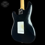 The back of a black Fender electric guitar, likely a Stratocaster, with a natural maple neck visible at the top, photographed against a solid black background. A 'Tone Shop' watermark is visible in the upper left corner.