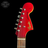 Close-up of a Fender Jaguar electric guitar headstock in glossy red, showing six silver tuning pegs, the Fender logo, and the Jaguar model name against a black background.