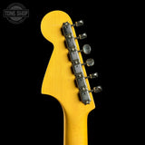 Close-up of the headstock of a yellow electric guitar against a black background, showing the tuning pegs and a Tone Shop watermark in the upper left corner.