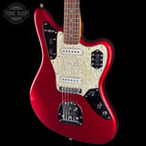 A red electric guitar with a white pearlescent pickguard and black control panels, shown against a black background with a Tone Shop watermark in the top left corner.