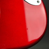 Close-up of a glossy red electric guitar body with a white pickguard and a visible screw on the upper right.