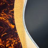 Close-up of a guitar's wooden neck and tortoiseshell patterned body against a dark background