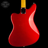The rear view of a red electric guitar body with a maple neck and black pickguard, shown against a solid black background with a Tone Shop watermark in the top left corner.