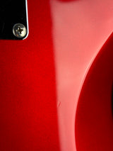 Close-up of a glossy red guitar body with a black hardware piece and screw visible in the upper left corner.