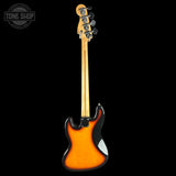 A classic electric bass guitar shown from the back, featuring a classic sunburst finish that transitions from bright orange to black, with a maple neck and black hardware, photographed against a solid black background.