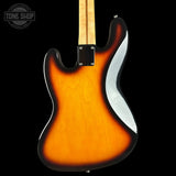 Rear view of a classic electric guitar body, featuring a sunburst finish that transitions from a bright orange center to black edges, with a white pickguard and a light wood neck visible at the top, set against a solid black background.