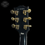 Guitar headstock with gold tuning pegs on a black background, featuring the Gibson logo.