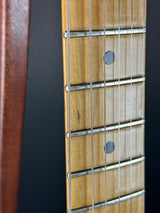 Close-up of a guitar fretboard with strings and frets on a dark background