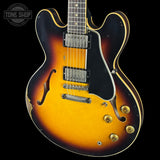 Electric guitar with a sunburst finish on a black background, featuring the Tone Shop logo.