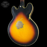 Back of a sunburst electric guitar with a visible brand logo in the corner.