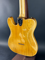 Close-up of a wooden guitar body with Fender logo on a dark background