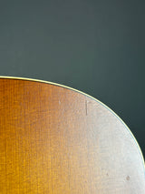 Close-up detail of a wooden instrument body corner, showing a warm brown wood grain finish against a dark gray background.