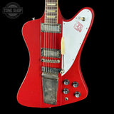 Red electric guitar with white pickguard on a black background, featuring the Gibson logo.