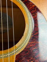 Close-up detail of an acoustic guitar's sound hole, showing the natural wood grain body, decorative rosette, and strings.