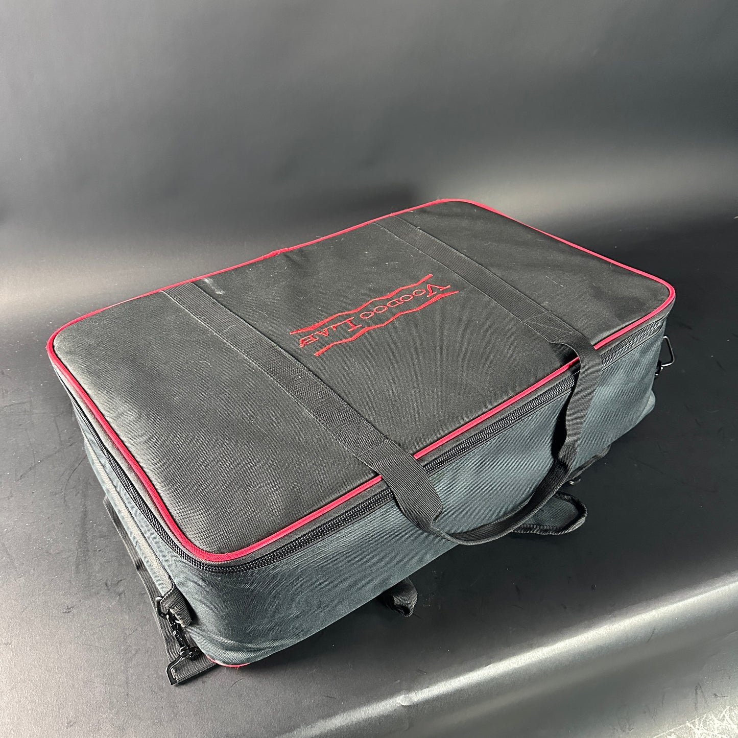 Gray carrying case with red trim and logo on a gray background