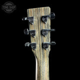 Close-up rear view of a guitar headstock with six black tuning pegs and a woodgrain finish, shown against a black background. A Tone Shop watermark is visible in the upper left corner.