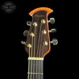 Close-up of the headstock of a Dunhill acoustic guitar against a solid black background, showing the brand name 'Dunhill' in gold script on the dark wood headstock with gold and silver tuning pegs.