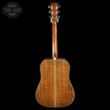Back view of a wooden acoustic guitar with 'Tone Shop' logo in the corner.