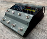 Guitar effects pedal with various controls on a wooden surface