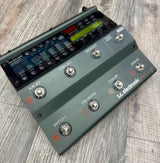 Guitar effects pedal with various controls on a wooden surface