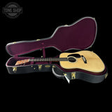Acoustic guitar in an open case with 'Tone Shop' branding.
