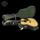 Acoustic guitar in a hard-shell case with 'Tone Shop' logo.