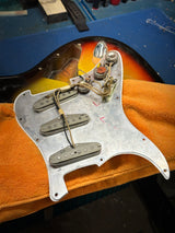 Guitar pickup cover on an orange towel with a blue background