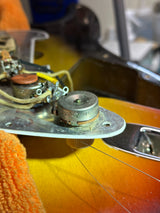 Close-up of a guitar's control panel with visible wiring and components.